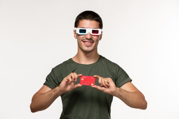 Front view young male in green t-shirt holding bank card in d sunglasses on white wall film lonely cinema