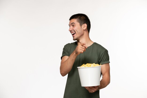 Front view young male in green t-shirt holding basket with cips on white wall film male lonely movies cinema