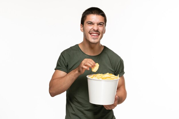 Front view young male in green t-shirt holding basket with potato cips watching movie on white wall lonely film movie cinema