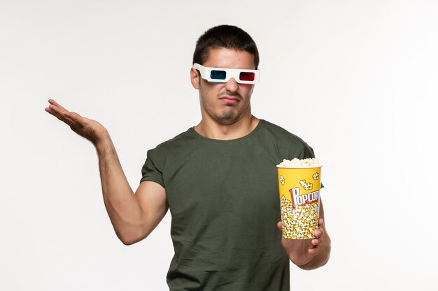 白い壁の映画で映画を見ているdサングラスでポップコーンを保持している緑のTシャツの正面図若い男性孤独な映画映画
