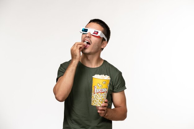 Вид спереди молодой мужчина в зеленой футболке, держащий попкорн в солнцезащитных очках d на белом столе, снимает одинокий кинотеатр мужские фильмы