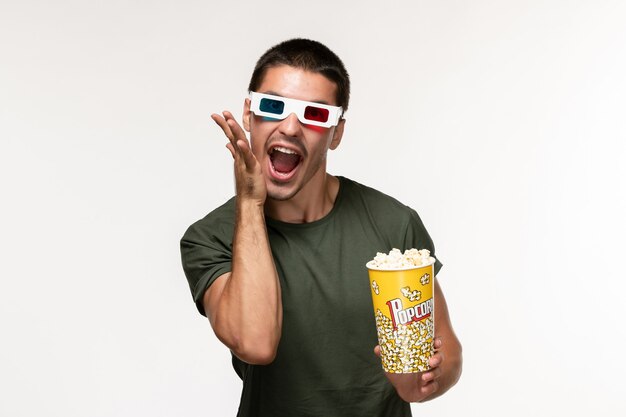 Front view young male in green t-shirt holding popcorn package in d sunglasses on light white wall film lonely cinema male movie