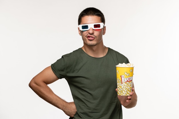 白い壁のフィルム孤独な映画の男性映画にdサングラスでポップコーンパッケージを保持している緑のTシャツの正面図若い男性