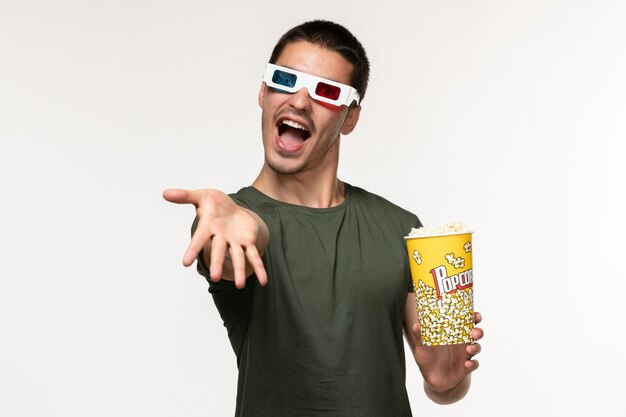 Front view young male in green t-shirt holding popcorn package in d sunglasses on white wall film lonely cinema male