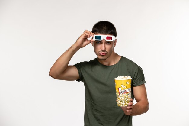 ポップコーンを保持し、白い壁の映画で映画を見ている-dサングラスで離陸する緑のTシャツの正面図若い男性孤独な映画の男性映画