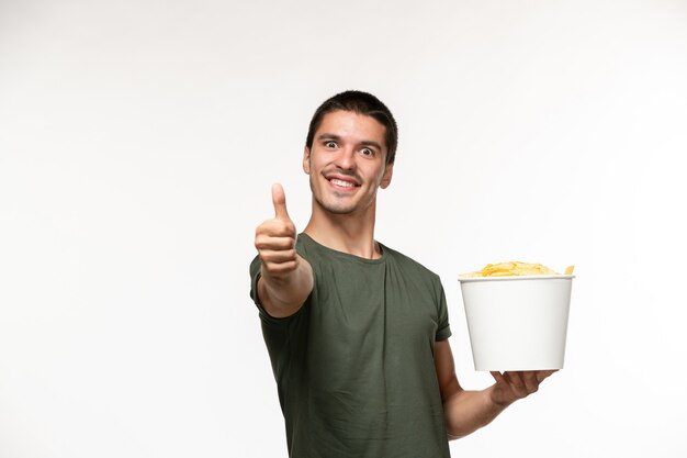 白い壁の孤独な映画映画映画の人のサインのように表示されているジャガイモのcipsを保持している緑のTシャツの正面図若い男性