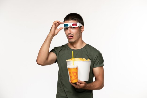 Вид спереди молодой мужчина в зеленой футболке, держащий картофельные чипсы с содовой в солнцезащитных очках -d на белой стене, фильм мужской одинокий фильм