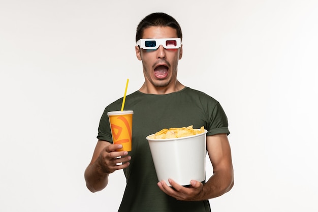 白い壁のフィルムの男性の孤独な映画にジャガイモのcipsとdサングラスのソーダを保持している緑のTシャツの正面図若い男性