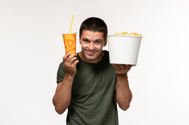 Front view young male in green t-shirt holding potato cips and soda on white wall film cinema male lonely movies