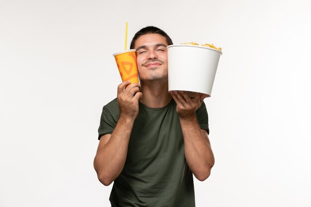 Front view young male in green t-shirt holding potato cips and soda on white wall film cinema male lonely