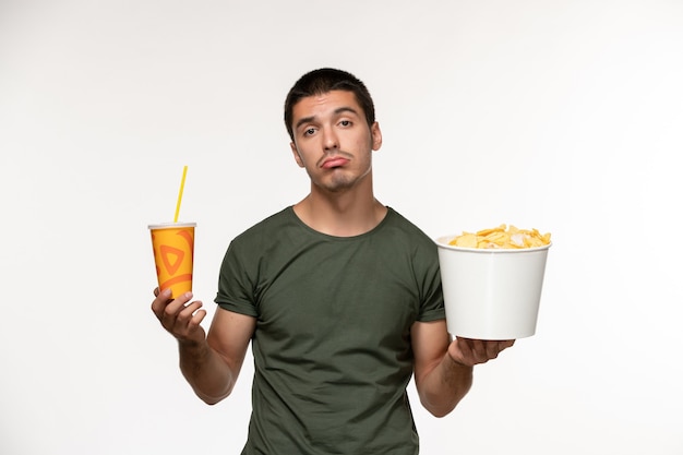 Front view young male in green t-shirt holding potato cips and soda on white wall film lonely cinema male movies