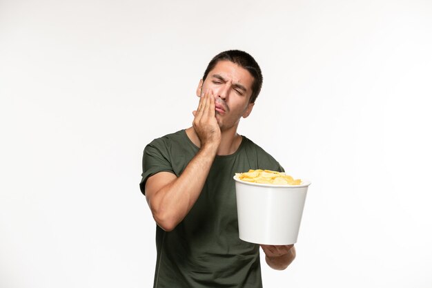 Front view young male in green t-shirt holding potato cips on the white wall lonely film movies cinema person