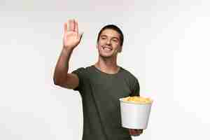 Foto gratuita giovane maschio di vista frontale in maglietta verde con le patatine fritte e saluto qualcuno sul cinema di film solitario maschio della persona del film della parete bianca