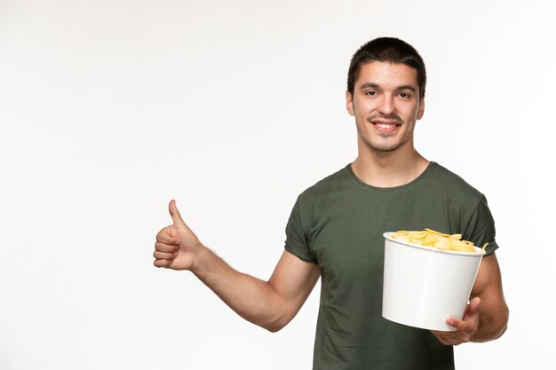 Front view young male in green t-shirt with potato cips and smiling on a white wall film person lonely movies cinema
