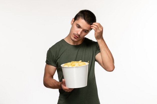 白い壁の映画人男性孤独な映画映画館で考えているジャガイモのcipsと緑のTシャツの正面図若い男性