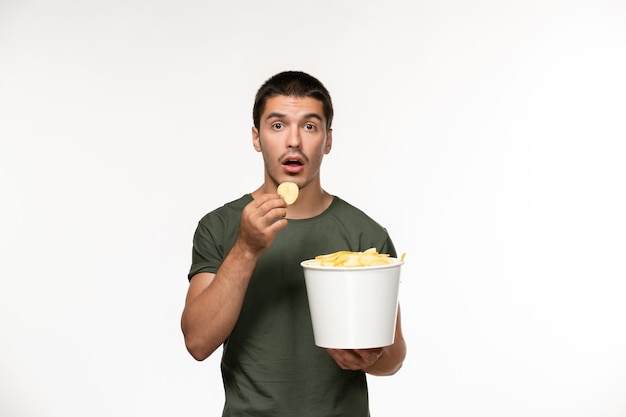 Giovane maschio di vista frontale in maglietta verde con patatine fritte sul muro bianco persona solitario film film cinema