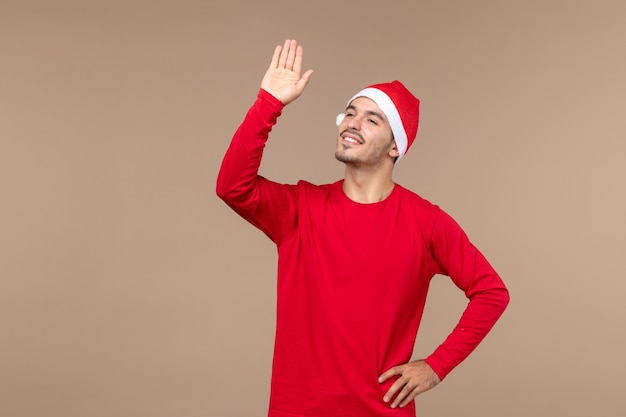 Вид спереди молодых мужчин приветствует и машет на коричневом фоне рождественские праздничные эмоции