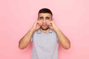 Free photo front view young male in grey shirt fake crying on pink