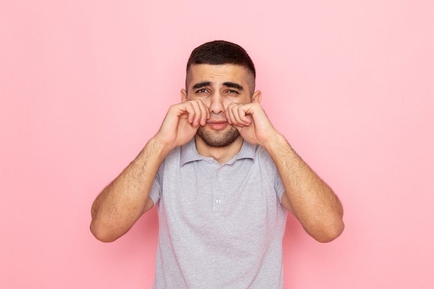 Front view young male in grey shirt fake crying on pink