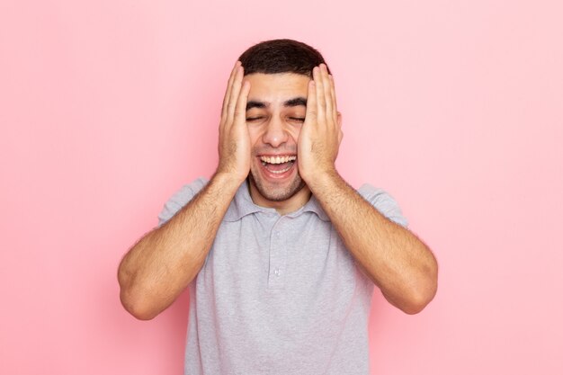 Front view young male in grey shirt laughing out loud on pink