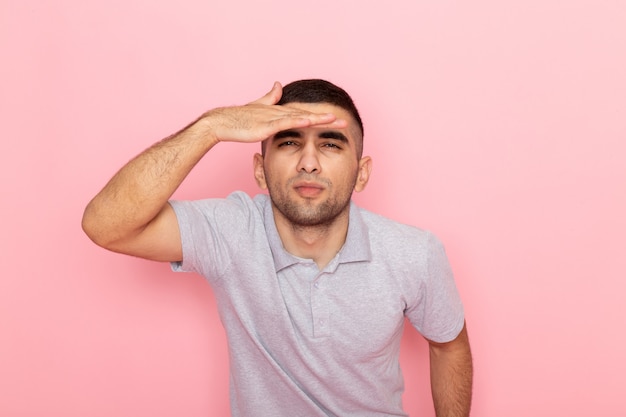 Free photo front view young male in grey shirt looking into the distance on pink