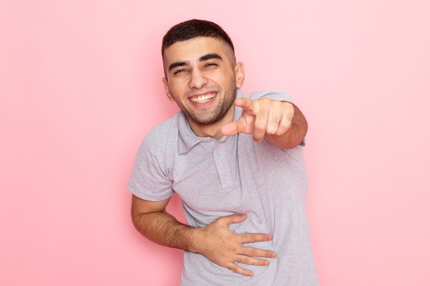 Front view young male in grey shirt posing and laughing on pink