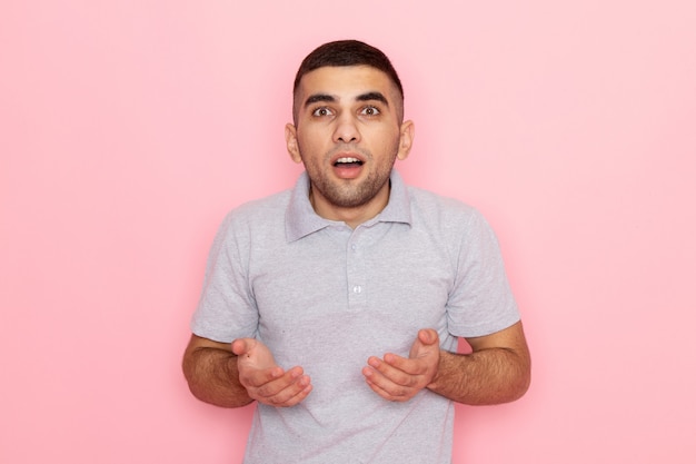 Free photo front view young male in grey shirt posing with shocked expression on pink