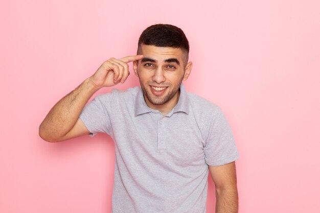 Front view young male in grey shirt posing with smile on pink