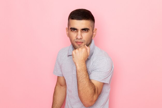 Front view young male in grey shirt showing his joy with fist on pink