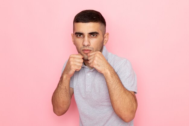 ピンクのボクシングスタンドに立っている灰色のシャツで正面の若い男性