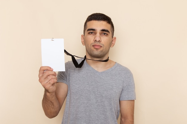 Foto gratuita giovane maschio di vista frontale in t-shirt grigia che tiene la carta d'identità