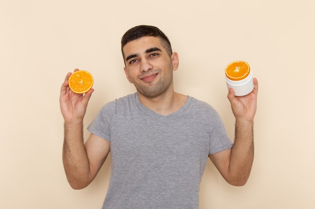 Вид спереди молодого мужчины в серой футболке с дольками апельсина на бежевом