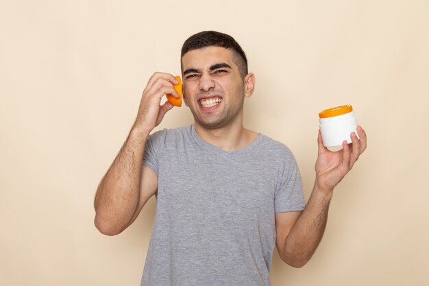 Front view young male in grey t-shirt holding orange slices on beige