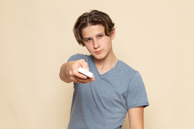 Молодой мужчина в серой футболке с пультом дистанционного управления, вид спереди