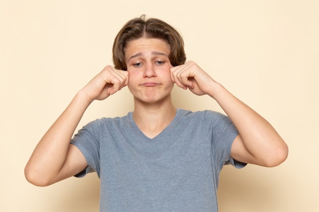 A front view young male in grey t-shirt posing and fake crying