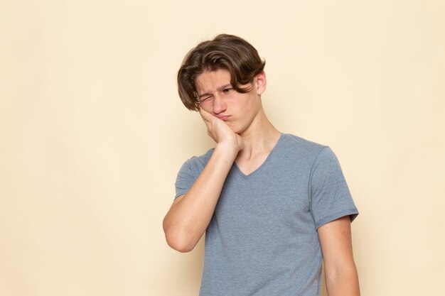 Молодой мужчина в серой футболке позирует с зубной болью