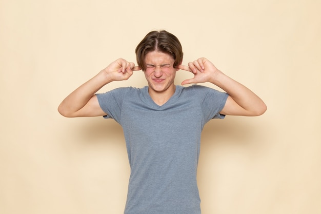 A front view young male in grey t-shirt posing shutting his ears