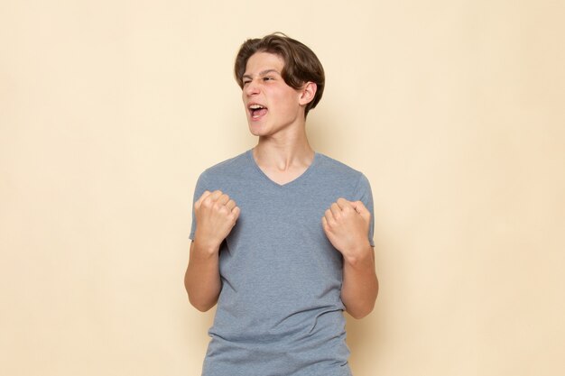 A front view young male in grey t-shirt posing with delighted expression