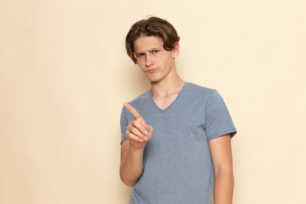 A front view young male in grey t-shirt posing with displeased expression