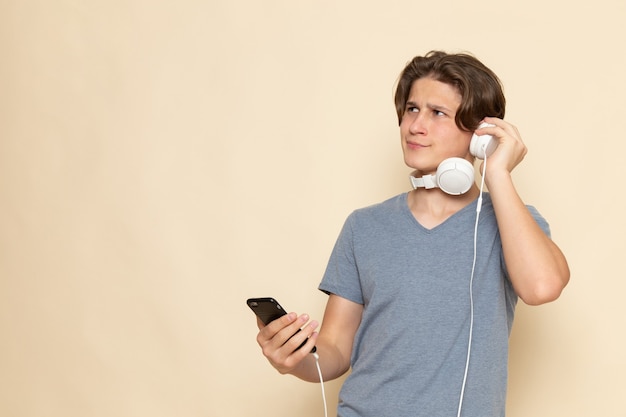 A front view young male in grey t-shirt using phone listening to music