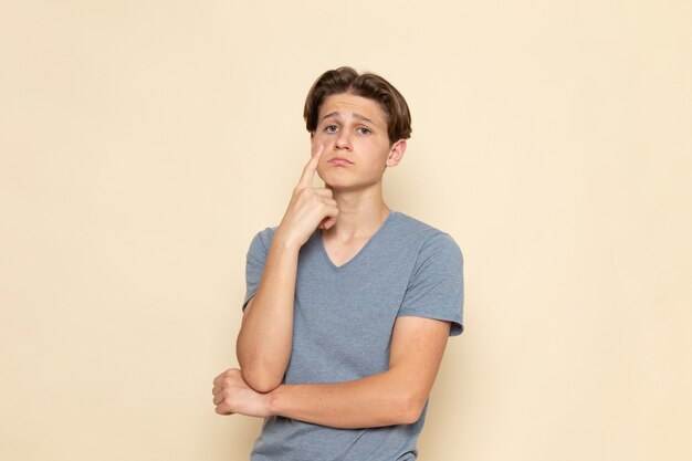 A front view young male in grey t-shirt with saddened expression