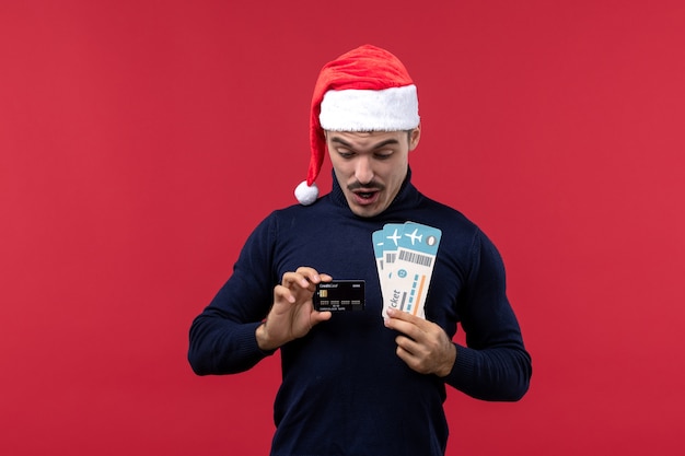 Free photo front view young male holding bank card and tickets on red background