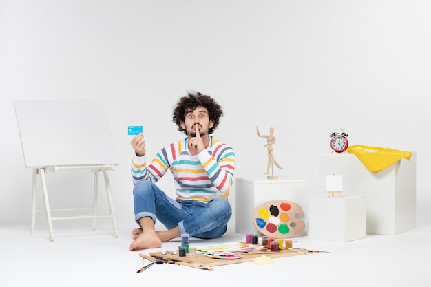 Free photo front view of young male holding bank card on white wall