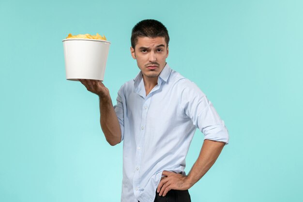 Front view young male holding basket with potato chips on a blue surface