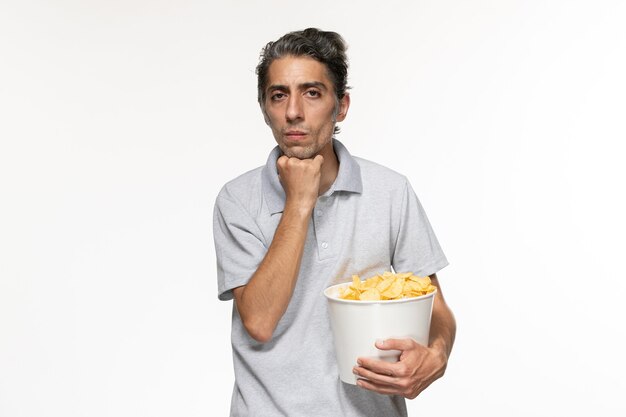 Front view young male holding basket with potato chips thinking on white surface