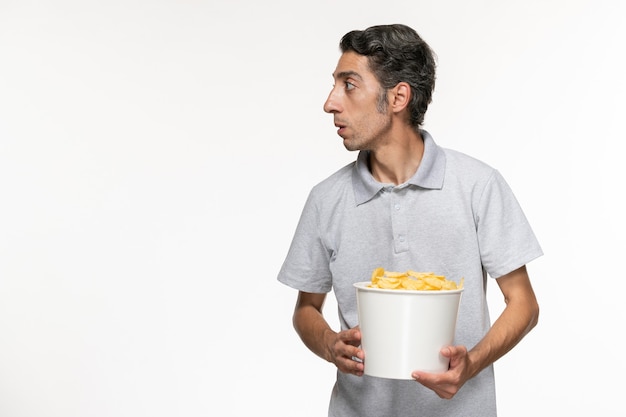 Front view young male holding basket with potato chips on white desk