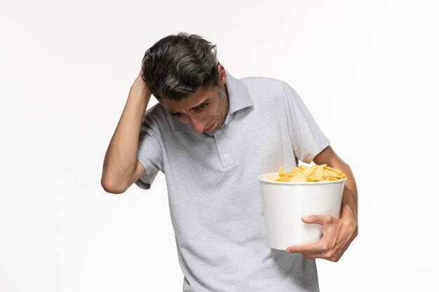 正面図白い表面にポテトチップスとバスケットを保持している若い男性