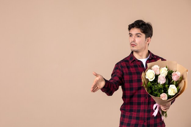 Front view young male holding beautiful flowers on brown wall