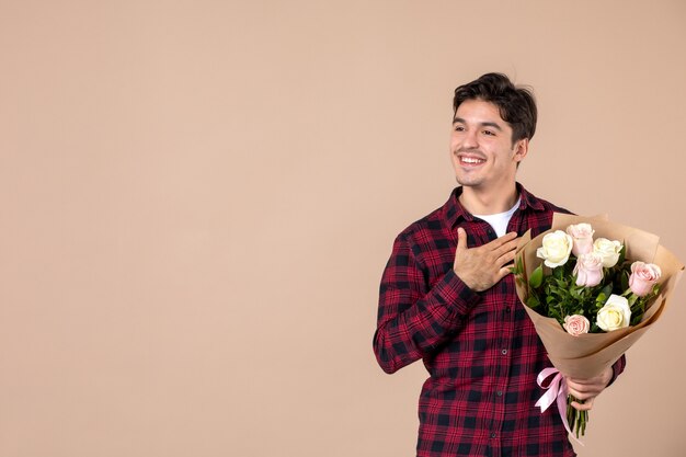 Front view young male holding beautiful flowers on brown wall