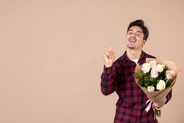 Front view young male holding beautiful flowers on brown wall